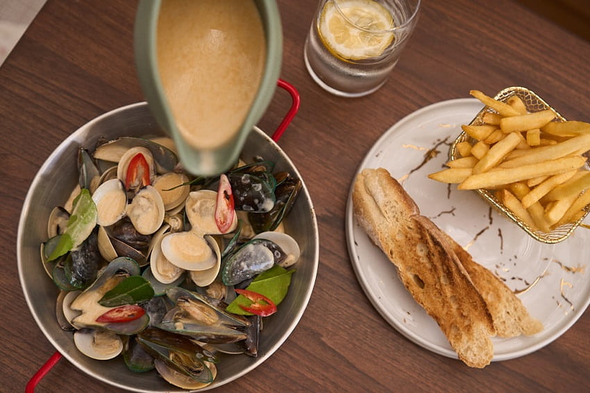 With an all-day dining approach, morning menus begin with crowd favourites like the Atlantic Breakfast, smoothie bowls, and specialty coffee, while lunchtime leans into lighter plates, fresh salads, and nourishing bowls designed for easy afternoons. As evening settles in, the kitchen shifts gears with dishes such as steak salmon and fresh mussels prepared in a variety of sauces.